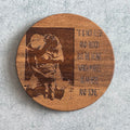 Wooden coaster with engraved design and text on a gray surface