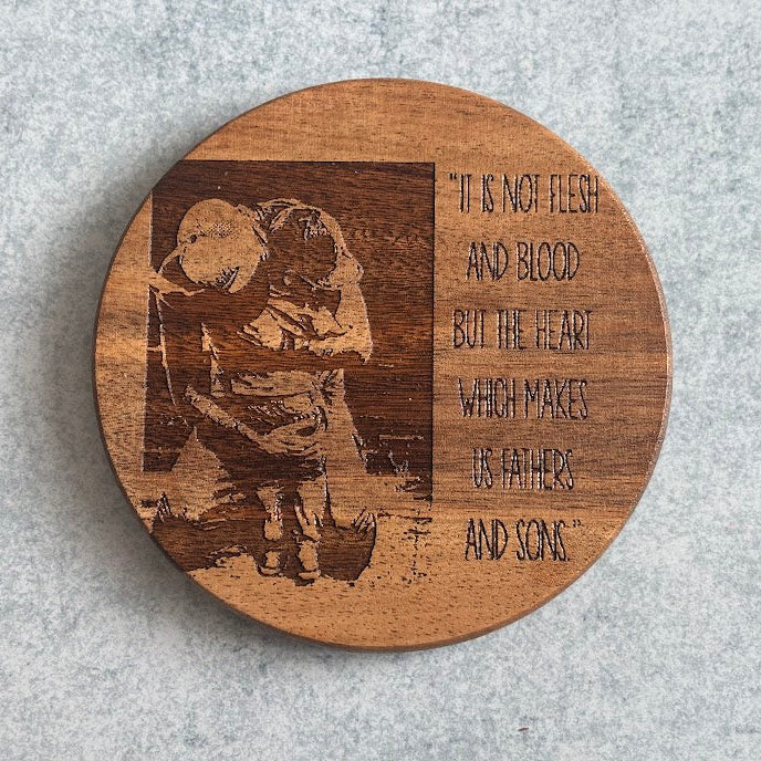 Wooden coaster with engraved design and text on a gray surface